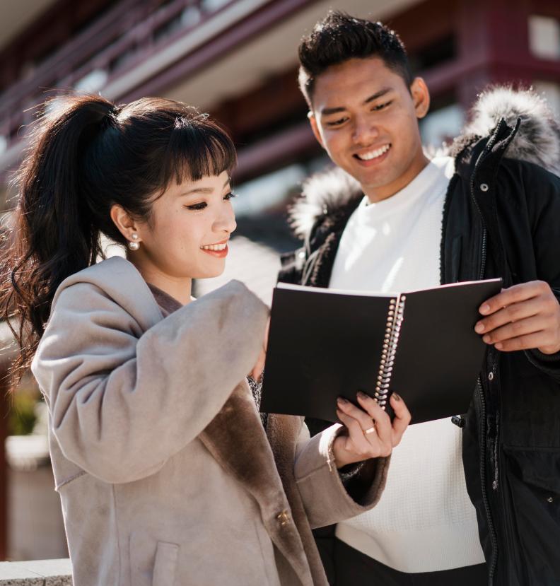 smiley couple ooking notebook together